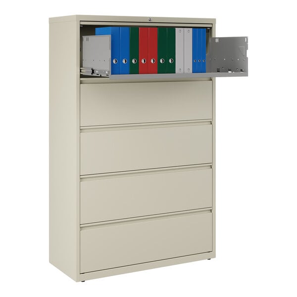 A five-drawer putty-colored lateral file cabinet with a roll-out binder storage shelf containing assorted binders.