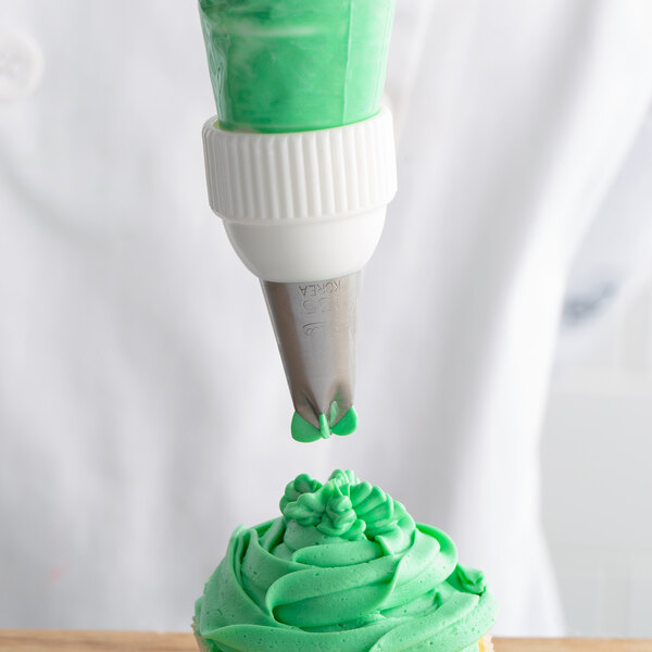 A person using an Ateco Drop Flower piping tip to decorate a cupcake with green frosting.