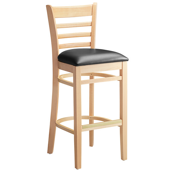 A Lancaster Table & Seating wooden bar stool with black vinyl seat.