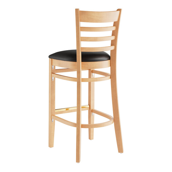 A Lancaster Table & Seating wooden ladder back bar stool with black vinyl seat