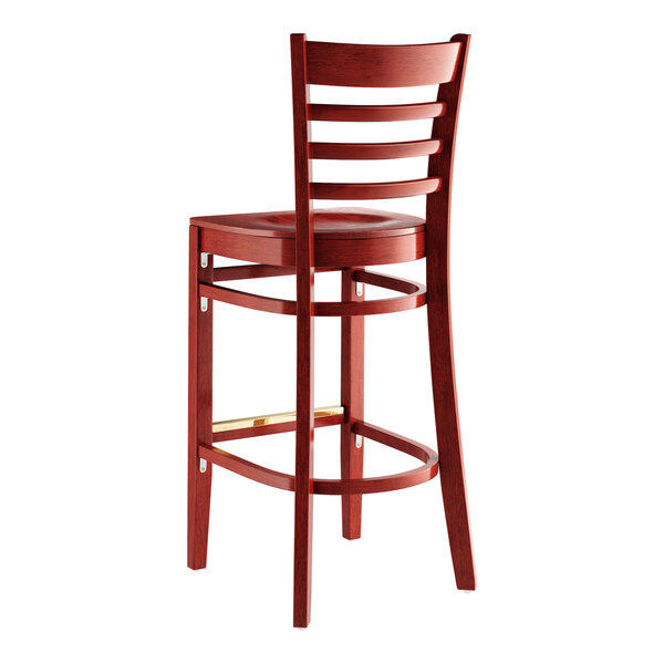 A Lancaster Table & Seating mahogany wood bar stool with a ladder back and wood seat.