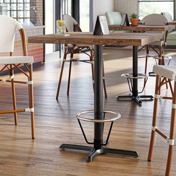 A Lancaster Table & Seating cast iron bar height table base with a metal foot ring.