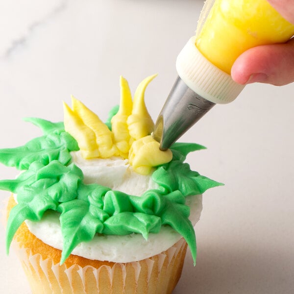 A person using an Ateco chrysanthemum piping tip to decorate a cupcake with green frosting.