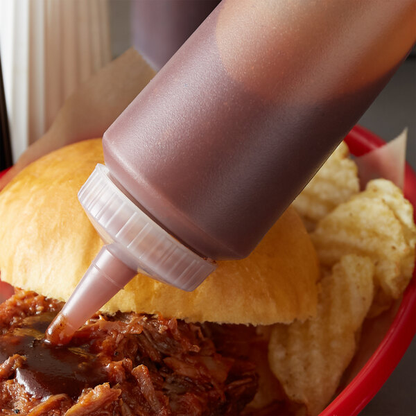 A Vollrath clear squeeze bottle of sauce being poured onto a burger.