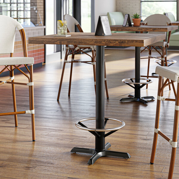A Lancaster Table & Seating black cast iron bar height table base with a metal foot ring.