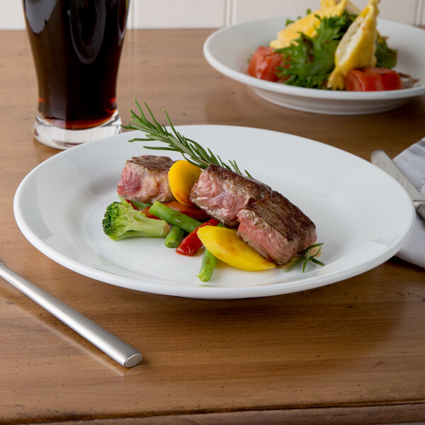 A close up of a Libbey Rigel Constellation white porcelain plate with meat and vegetables on it.