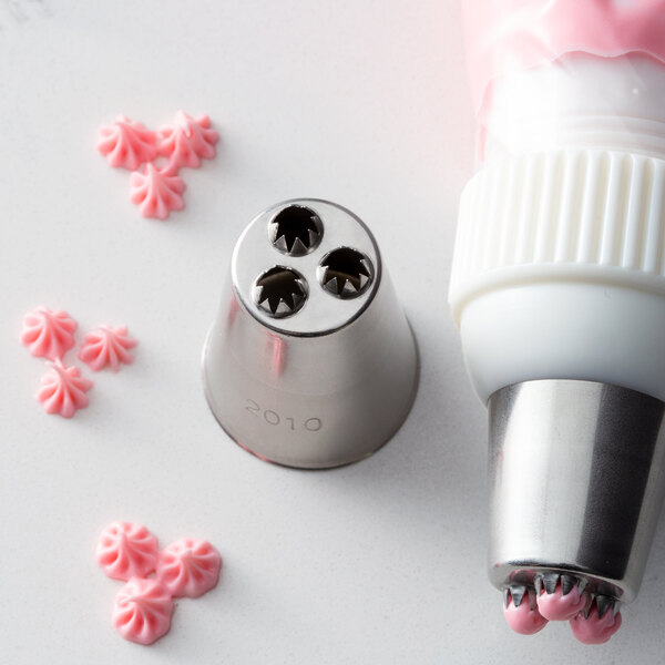A pastry bag with a white Ateco Triple Star piping tip and pink frosting sprinkles.