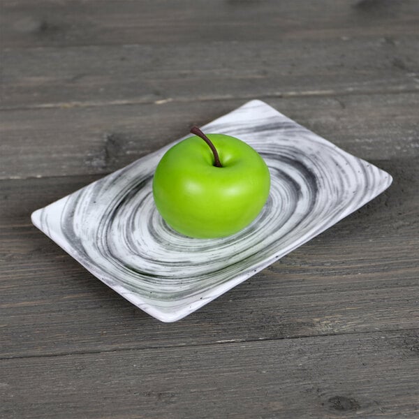 An Elite Global Solutions Van Gogh black rectangular melamine plate with a green apple on it.