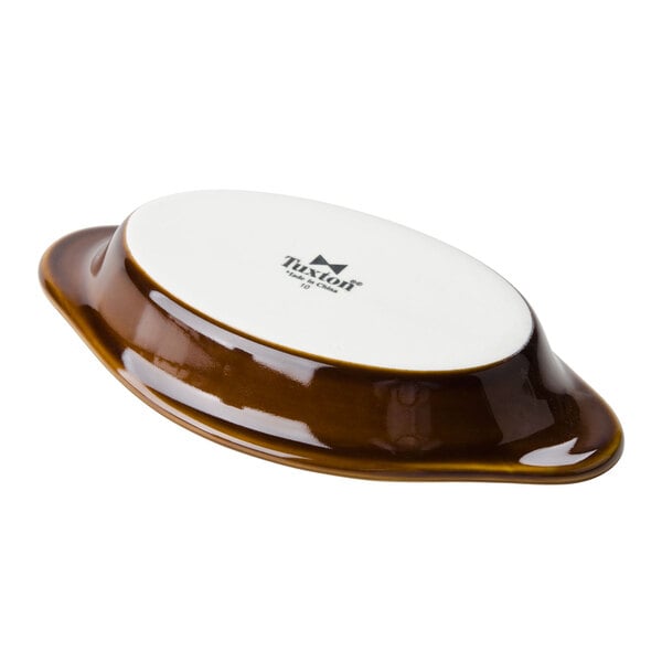 A close-up of a white and brown Tuxton oval dish with a lid.