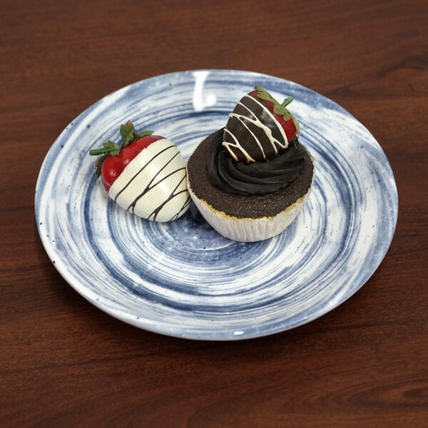 An Elite Global Solutions navy melamine plate with a chocolate cupcake and a strawberry on it.