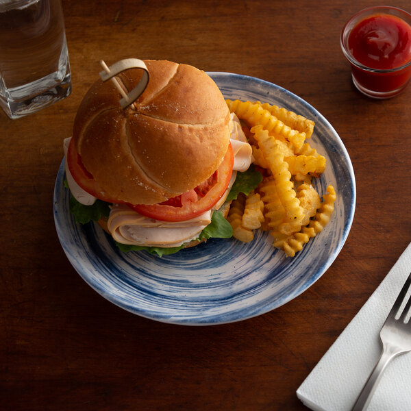 An Elite Global Solutions Van Gogh navy melamine plate with a sandwich and fries on it.