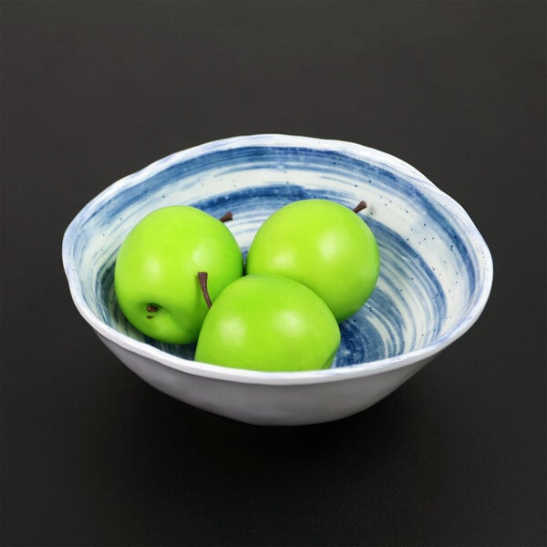 A navy oval melamine bowl filled with green apples.