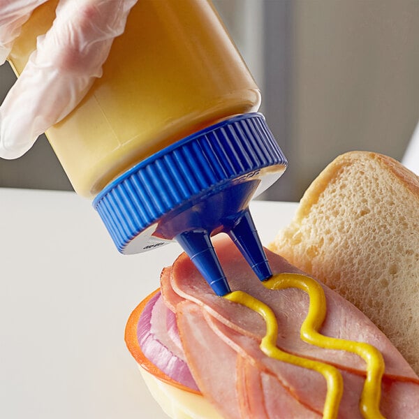 a person pouring mustard on a sandwich