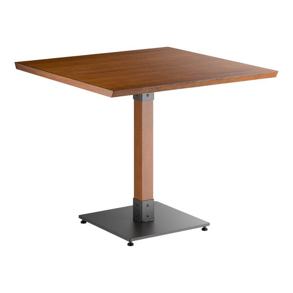 A square wooden table with a rustic walnut finish, featuring a single central wooden support and a black metal base.