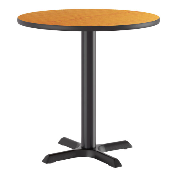 A round standard height table with a reversible walnut and oak top and a black cast iron base.
