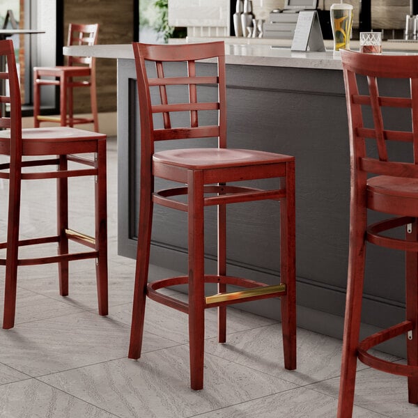 A Lancaster Table & Seating mahogany wood bar stool with a mahogany wood seat.