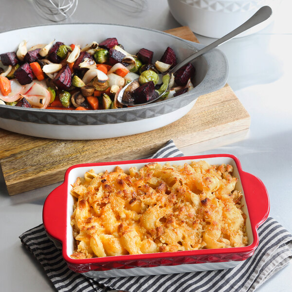 A Tuxton oval casserole dish filled with food next to a bowl of food.