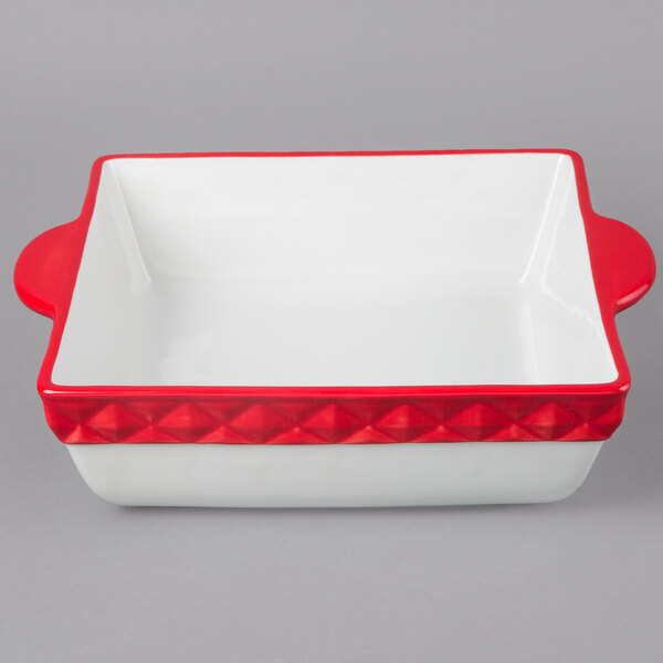A white square Tuxton casserole dish with red trim.