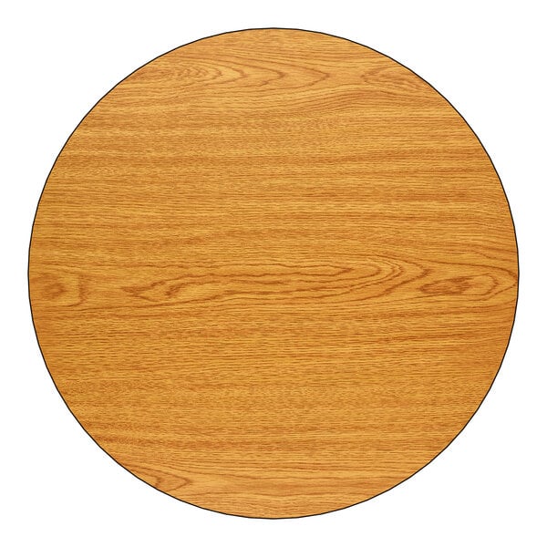 A round, 24-inch reversible table top with a wood grain finish, shown in an oak color.