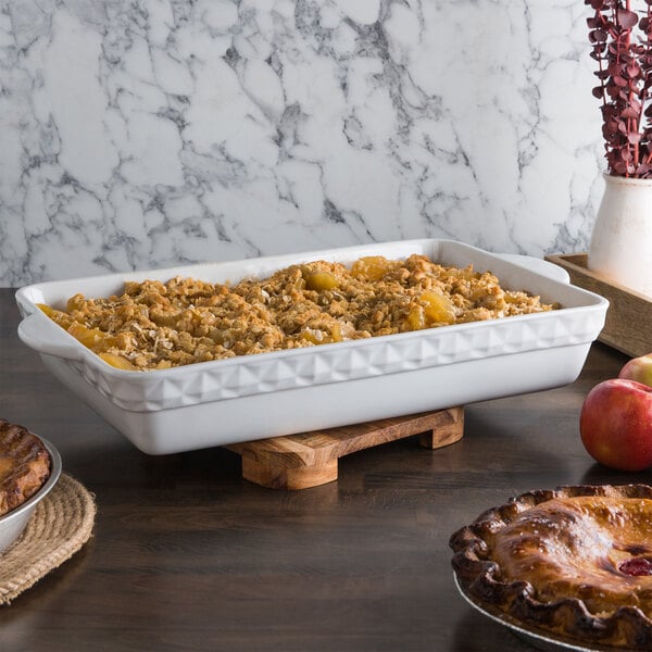 A Tuxton bright white rectangular china casserole dish with food in it on a table.