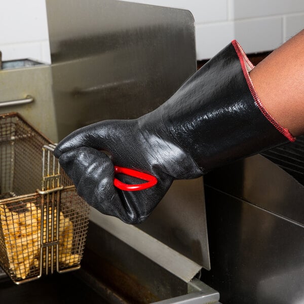 A person wearing a red San Jamar neoprene oven mitt holding a basket of fries.