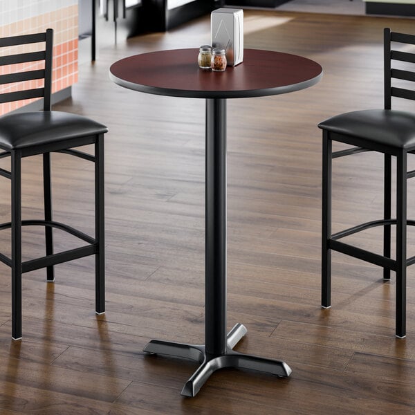 A round bar-height table with a reversible cherry and black top, supported by a black cast iron base.