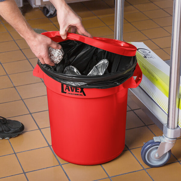 A hand putting foil in a red Lavex trash can.