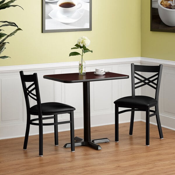 A Lancaster Table with a 24" x 30" reversible cherry/black top and cross cast iron base with a cup of coffee on it.