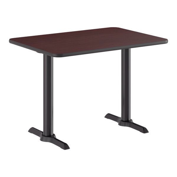 A rectangular standard height table with a reversible cherry and black top and a cast iron base.