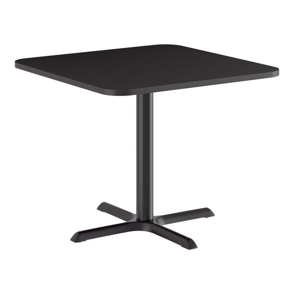 A square black standard height table with a reversible top and a cast iron base.