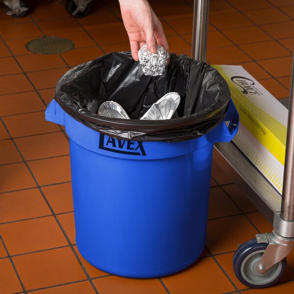 A person putting foil in a Lavex blue trash can.