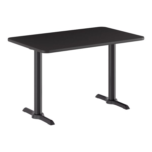 A rectangular black standard height table with a reversible top and two cast iron pedestal bases.