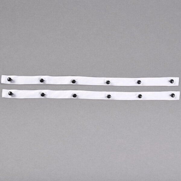 Two black button strips with white dots on them being held in a couple of hands.