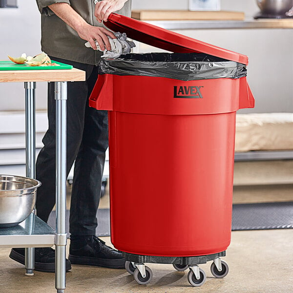 A man standing next to a red Lavex commercial trash can.