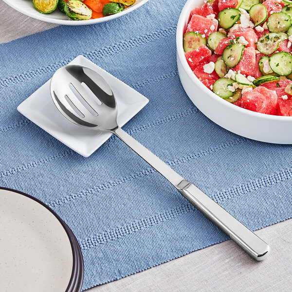 A plate with a bowl of watermelon and cucumber salad with an American Metalcraft stainless steel slotted spoon on it.