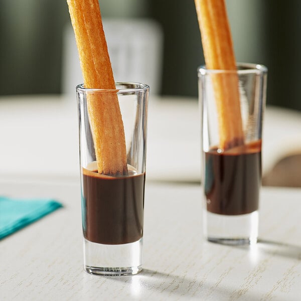 Churros in Acopa shot glasses with chocolate syrup.