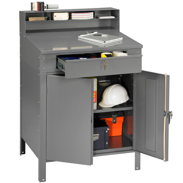 A Tennsco medium gray steel cabinet shop desk with an enclosed cabinet and a white hard hat on top.