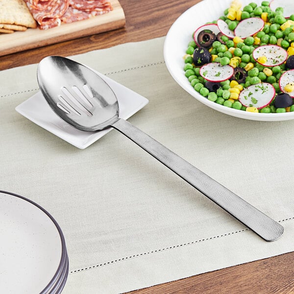 A slotted spoon on a plate of food.
