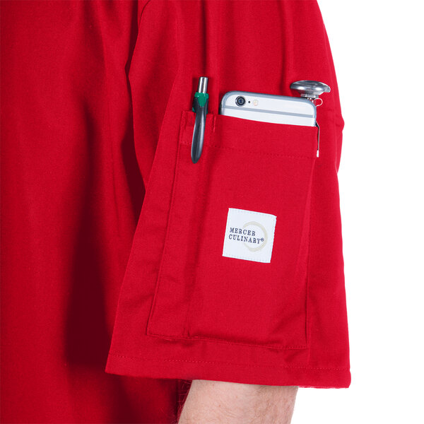 A person wearing a red Mercer Culinary Millennia Air cook jacket with a pocket full of a phone and a pen.
