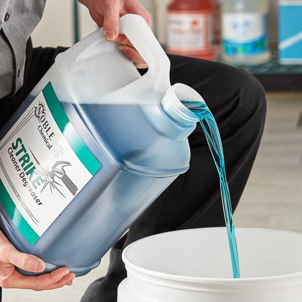 A man pouring Noble Chemical Strike All Purpose Concentrated Cleaner Degreaser into a bucket.