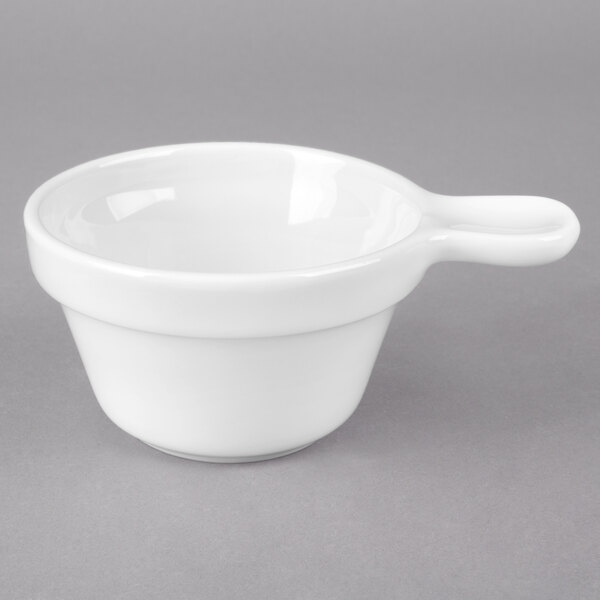 A close up of a Tuxton porcelain white soup cup with a handle.