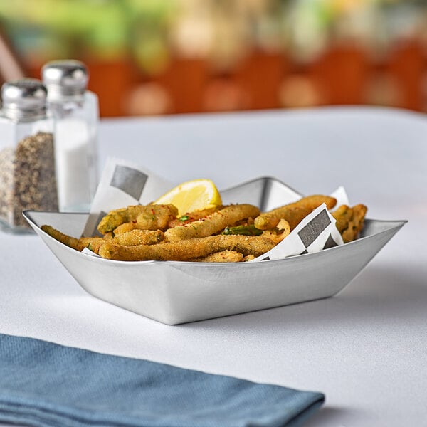 A stainless steel Tablecraft serving basket with a bowl of fried food and lemon wedges on a table.