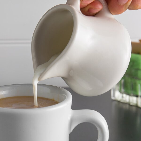 a person pouring milk into a cup