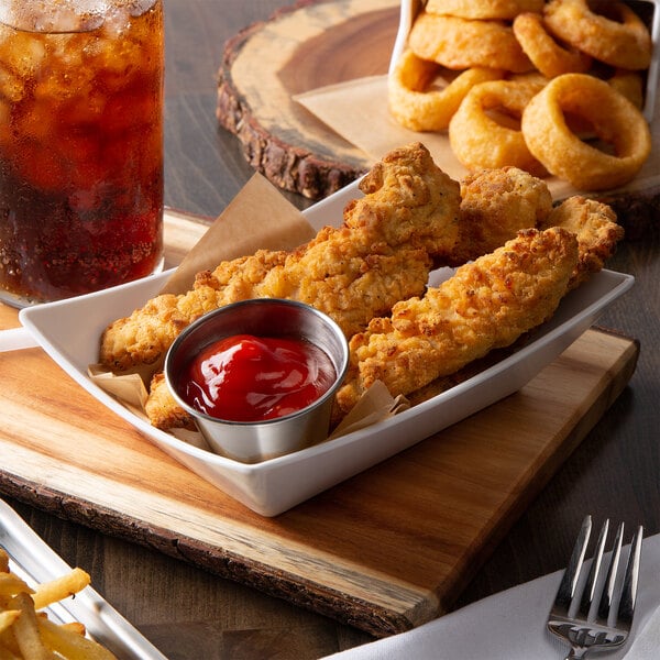 chicken tenders in serving basket with ketchup next to soda and onion rings