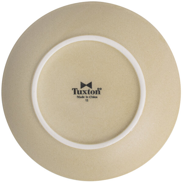 A Tuxton TuxTrendz Zion matte beige coupe plate with a white rim.