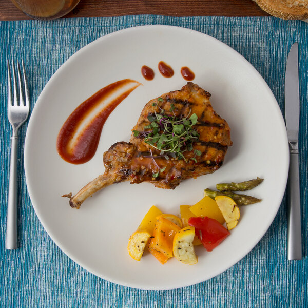 A Tuxton TuxTrendz matte white china plate with a plate of food with a fork and knife.