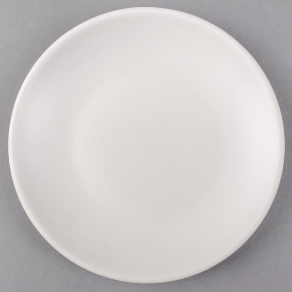 A Tuxton TuxTrendz Zion matte white coupe plate on a gray surface.