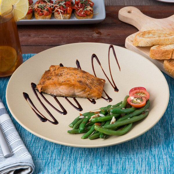 A Tuxton TuxTrendz matte beige china plate with a piece of grilled salmon and green beans on a table.