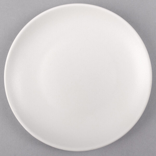 A Tuxton TuxTrendz Zion matte white coupe plate on a gray surface.
