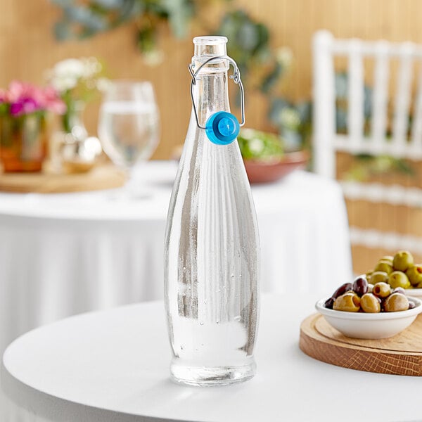 A clear Libbey glass bottle with a blue wire bail lid on a table.